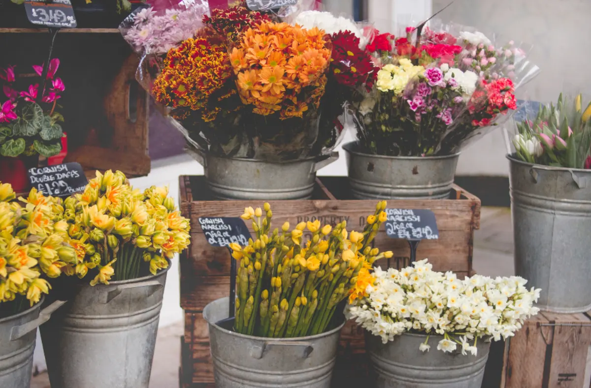 Cubos con ramos de flores frescas en la entrada de una floristería