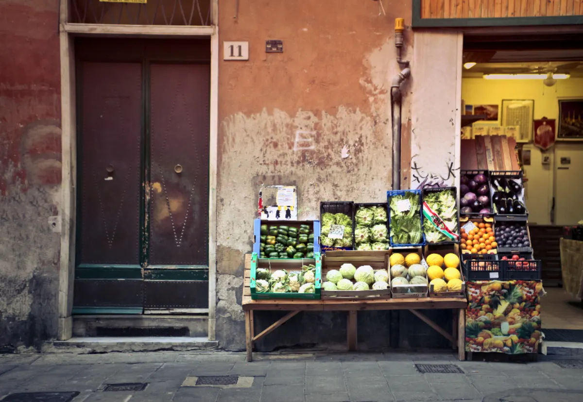 Puesto de fruta y verdura en la puerta de una tienda de alimentación